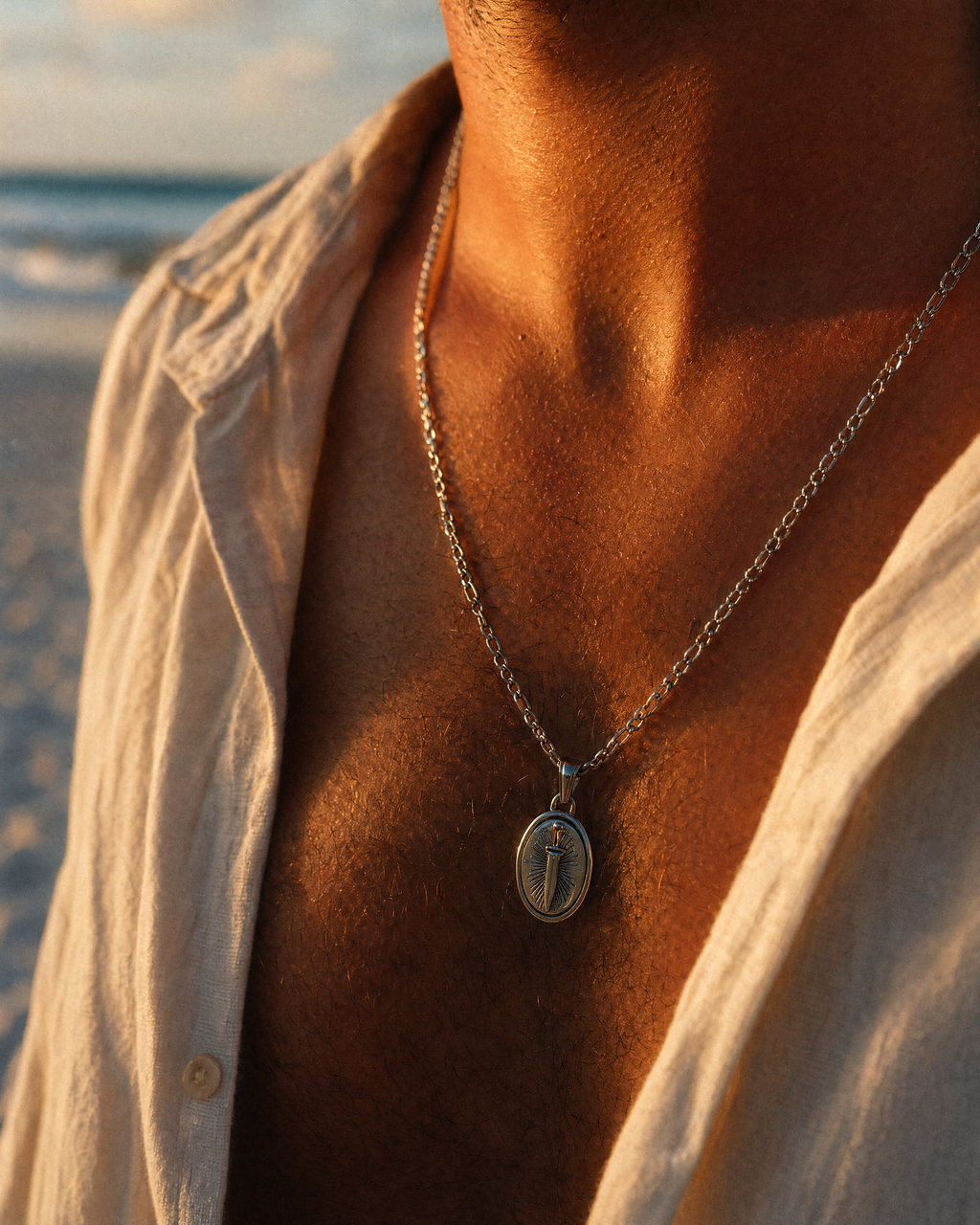 Silver stainless steel dagger pendant necklace worn on a man's chest, close-up of oval pendant